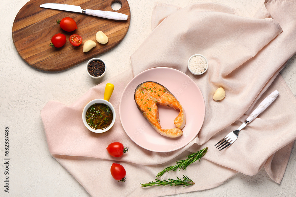 Plate of tasty salmon steak with tomatoes, sauce and garlic on white background