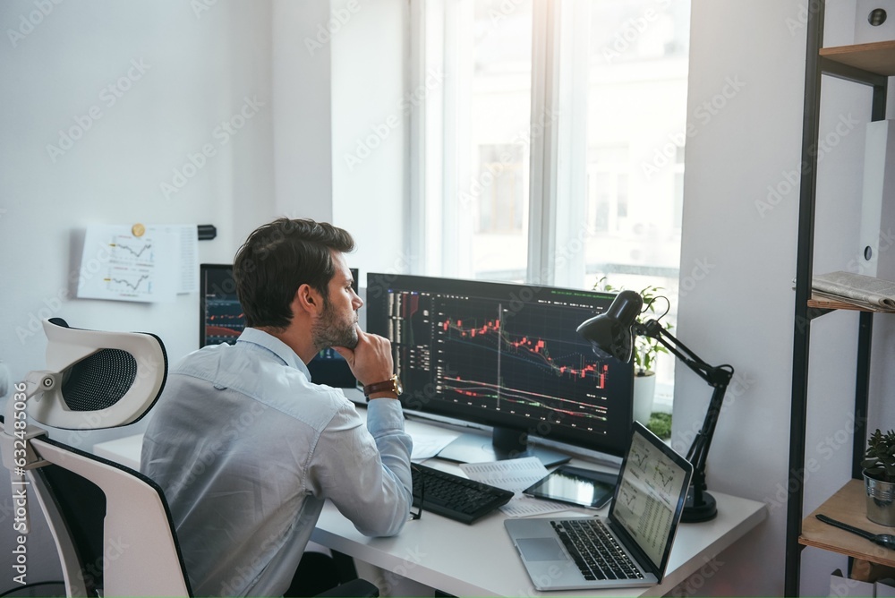 Trading on world markets. Young stock market broker analyzing data and graphs on multiple computer s