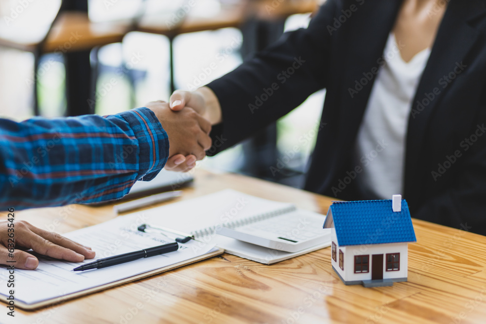 Businessman and real estate agent shaking hands after negotiating home purchase agreement.