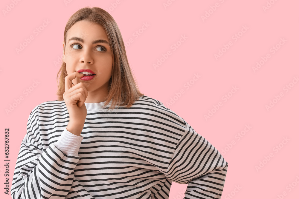 Thoughtful young woman in striped sweatshirt on pink background