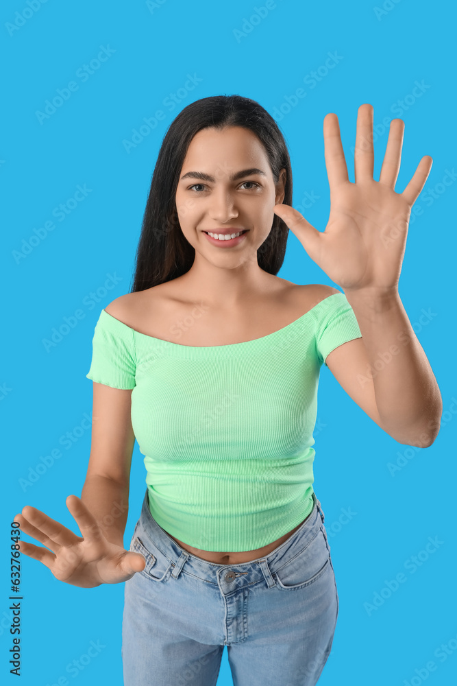 Beautiful young woman showing hands on blue background