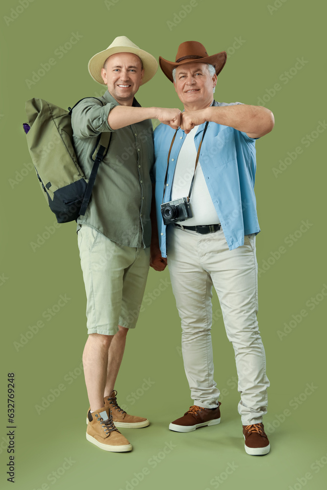 Mature brothers bumping fists on green background