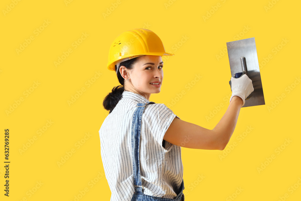 Female decorator with trowel on yellow background