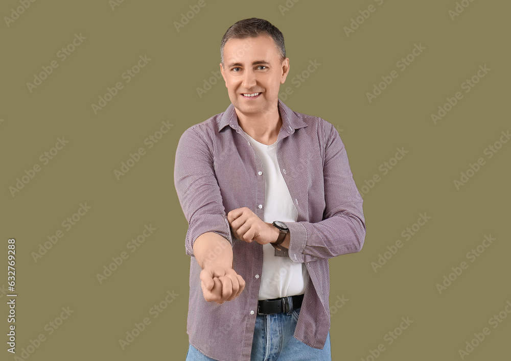 Mature man rolling up his sleeve on green background