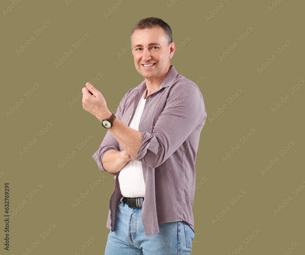 Mature man rolling up his sleeve on green background