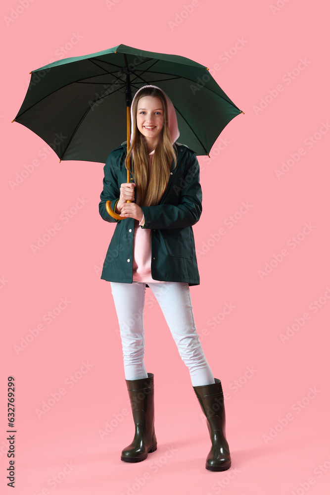 Teenage girl with green umbrella on pink background