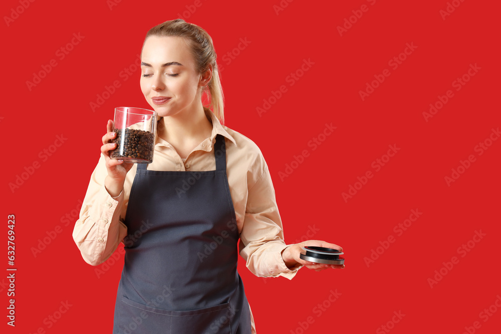 Young barista with jar of coffee beans on red background