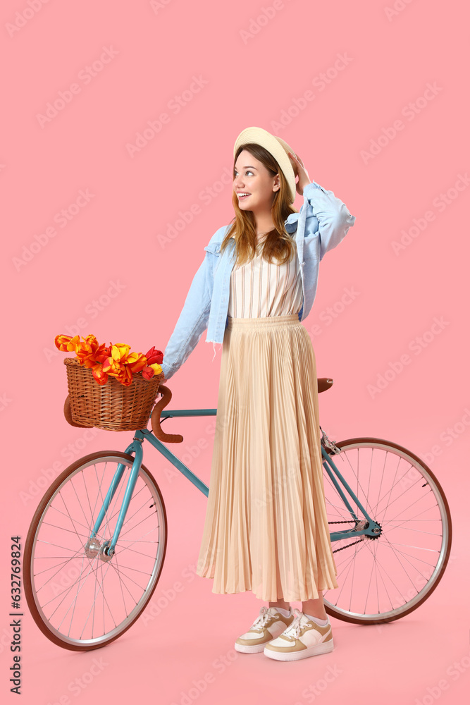 Young woman with bicycle on pink background