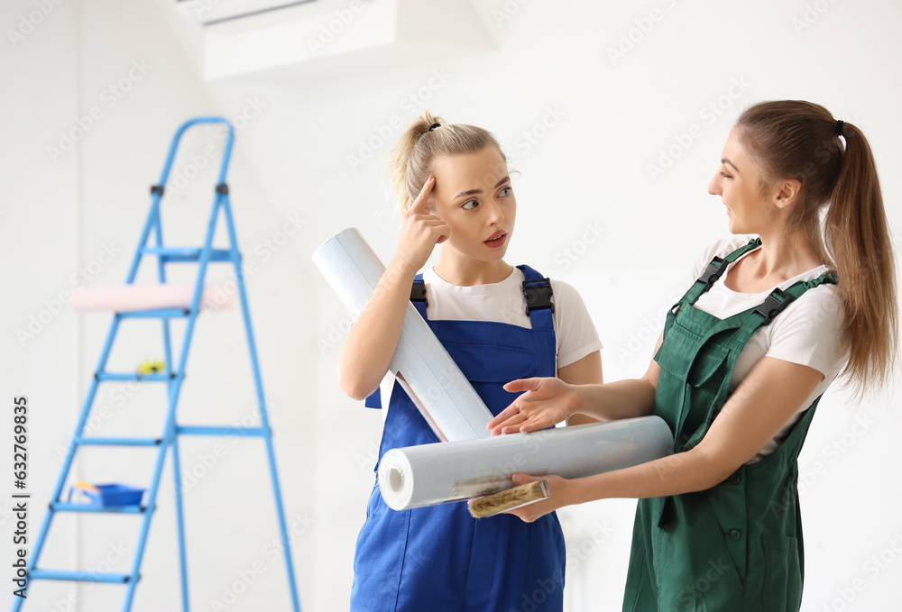 Female decorators with wallpaper rolls in room