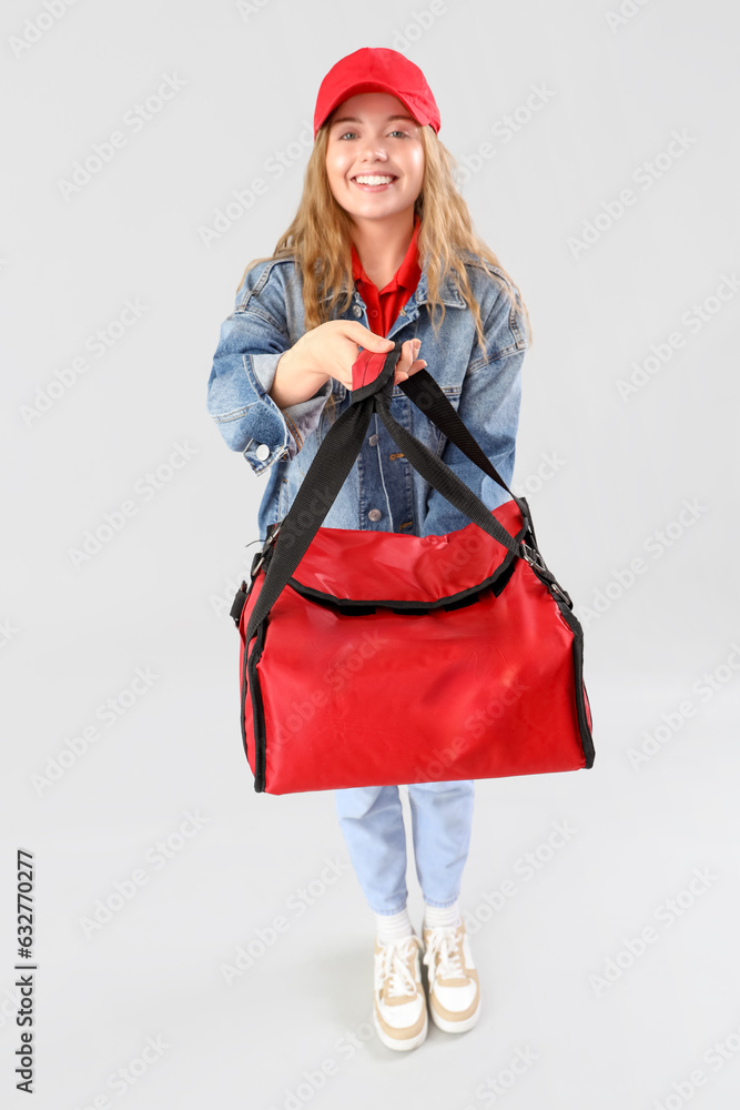 Female courier with thermal bag on grey background