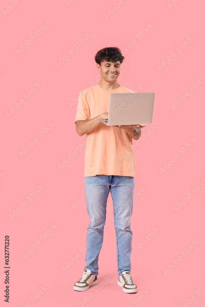 Male programmer working with computer on pink background