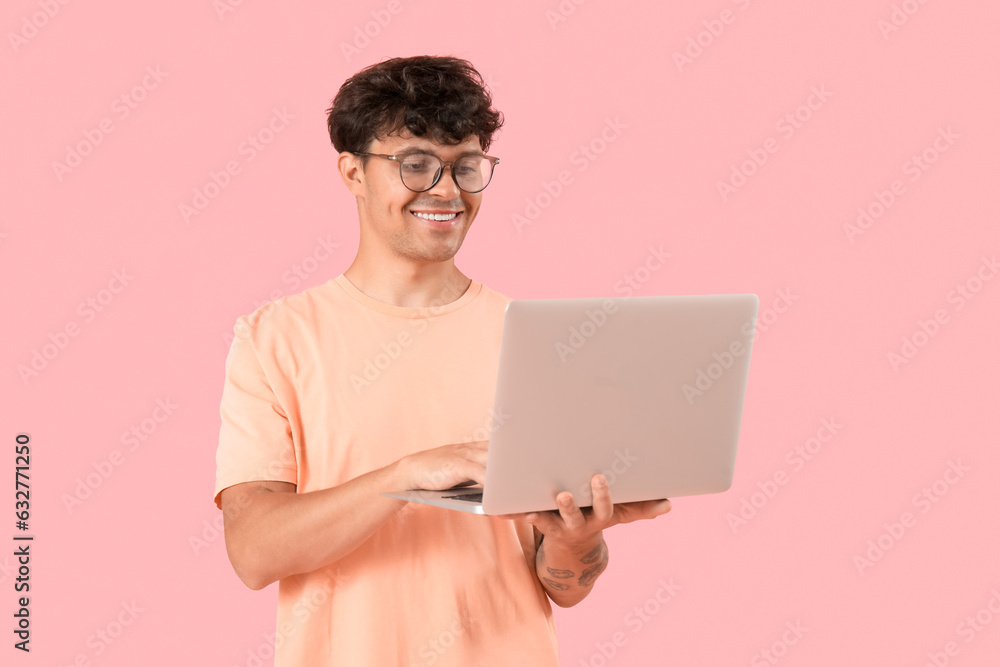 Male programmer working with computer on pink background