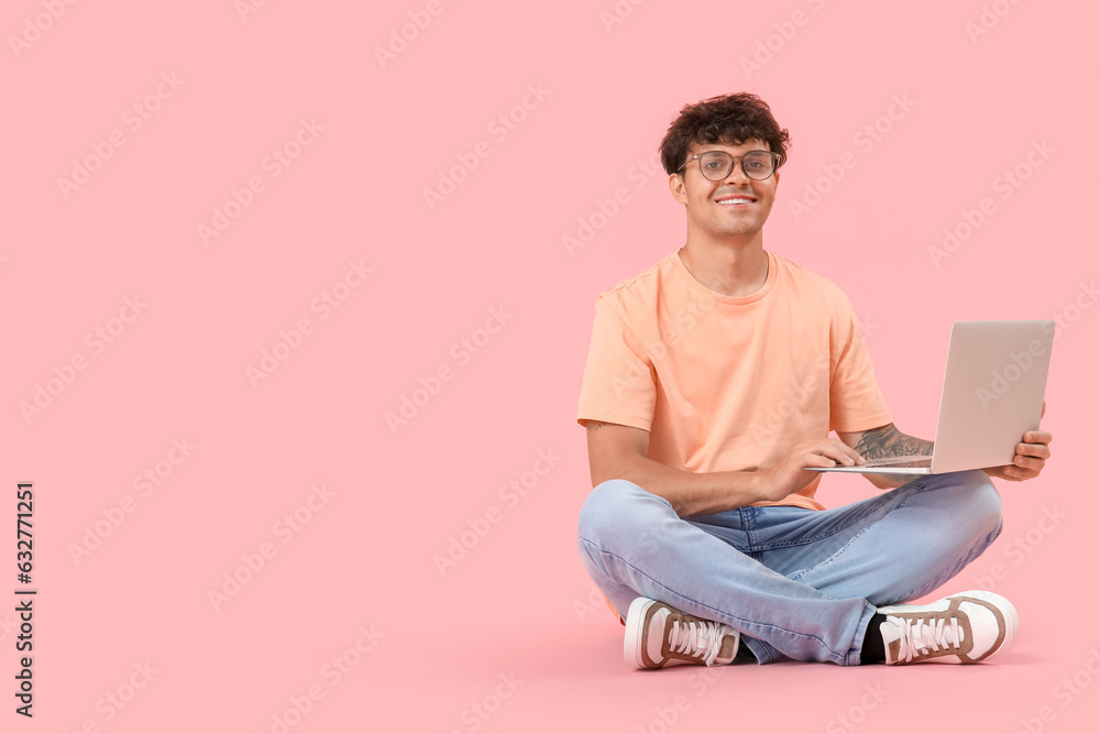 Male programmer working with computer on pink background