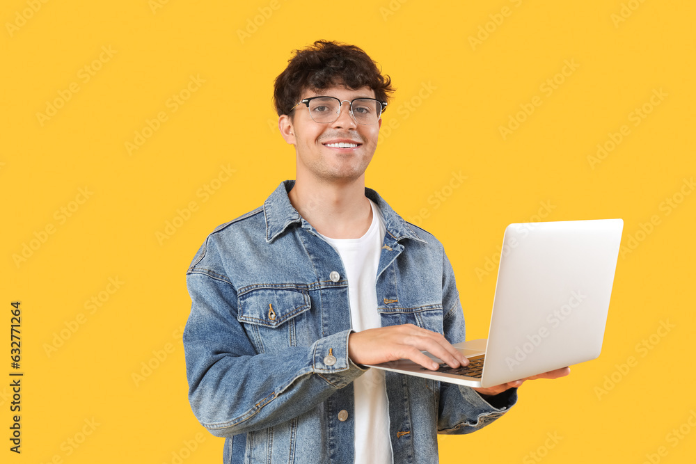 Male programmer working with laptop on yellow background