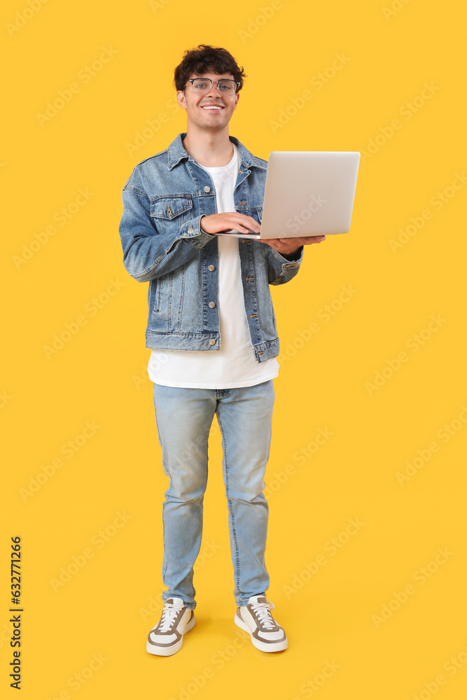 Male programmer working with laptop on yellow background