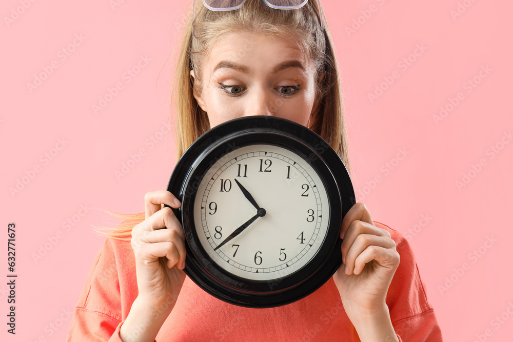 Young woman with clock on pink background, closeup. Deadline concept