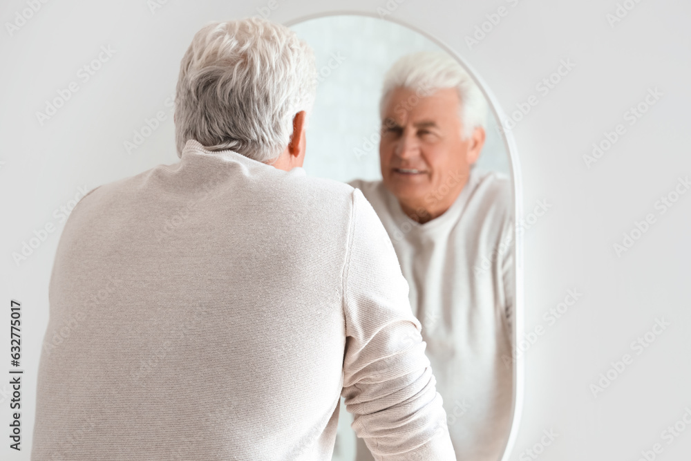 Senior man looking in mirror at home