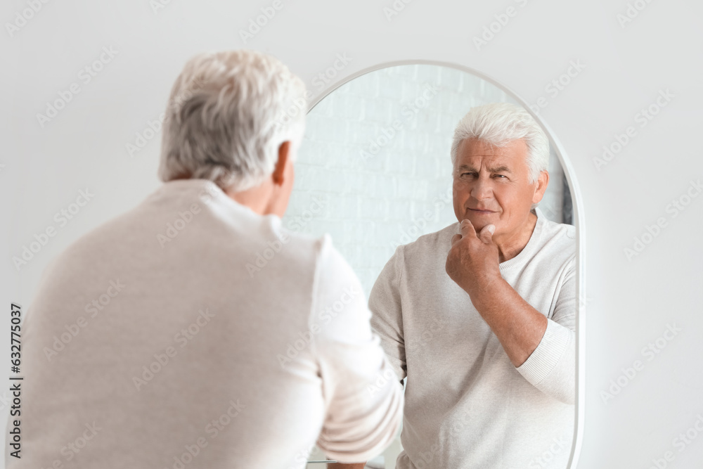 Senior man looking in mirror at home