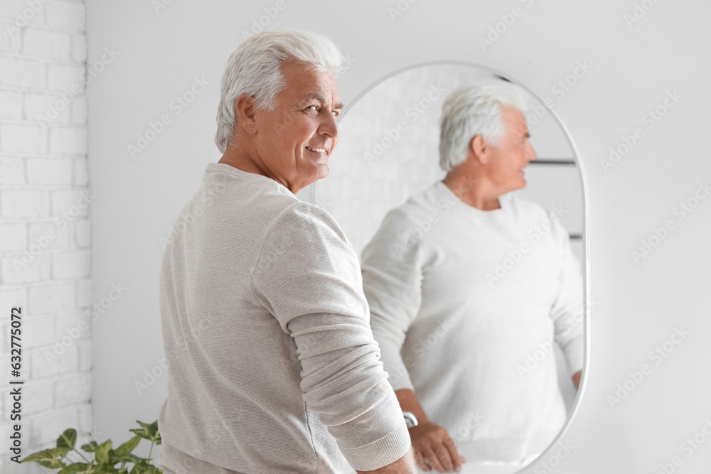 Senior man looking in mirror at home