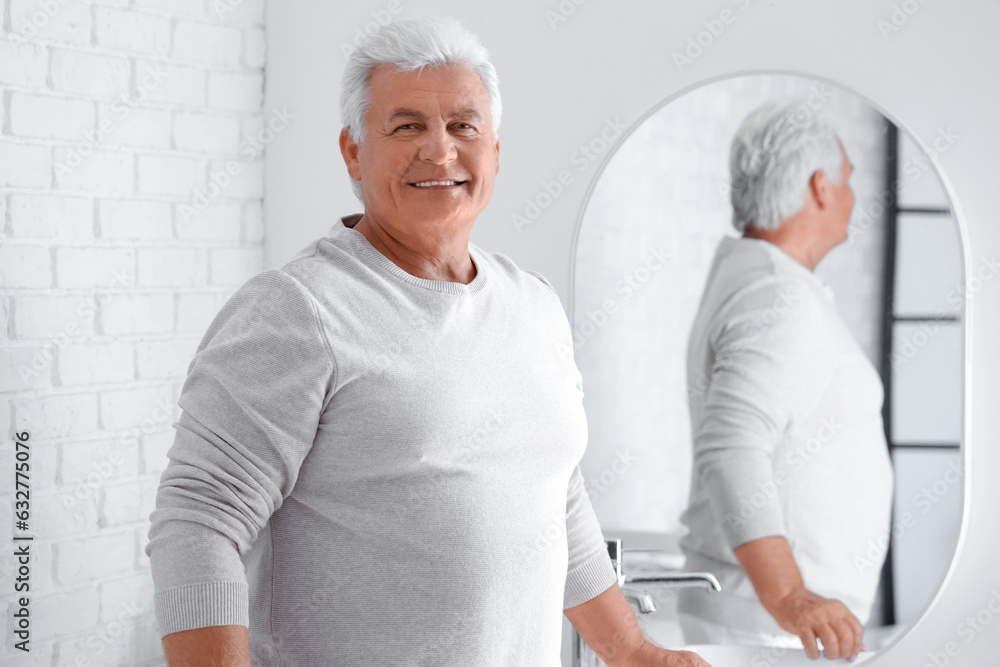 Senior man looking in mirror at home