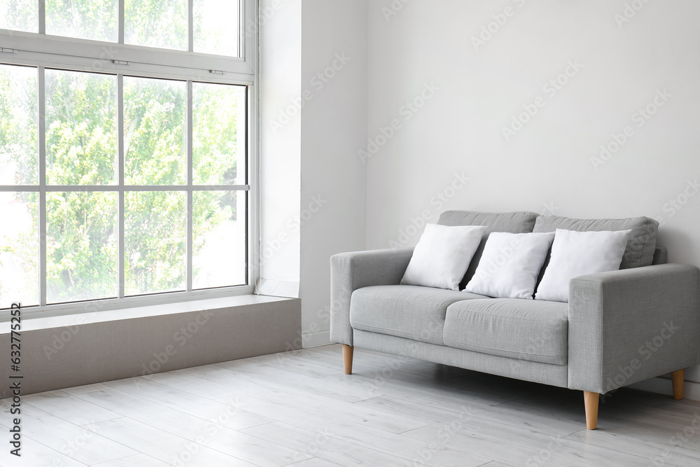 Grey sofa with pillows near white wall