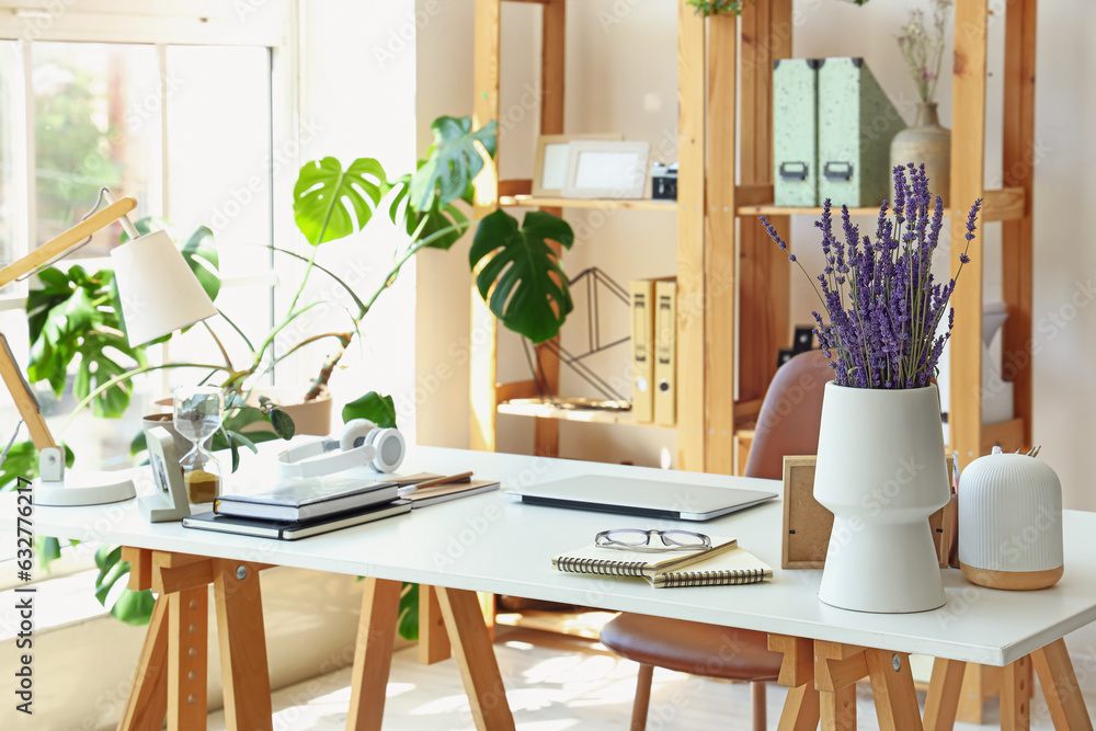 Modern workplace with laptop and lavender flowers in interior of office