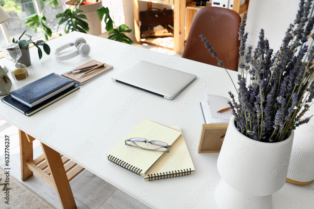 Laptop with stationery on desk in office