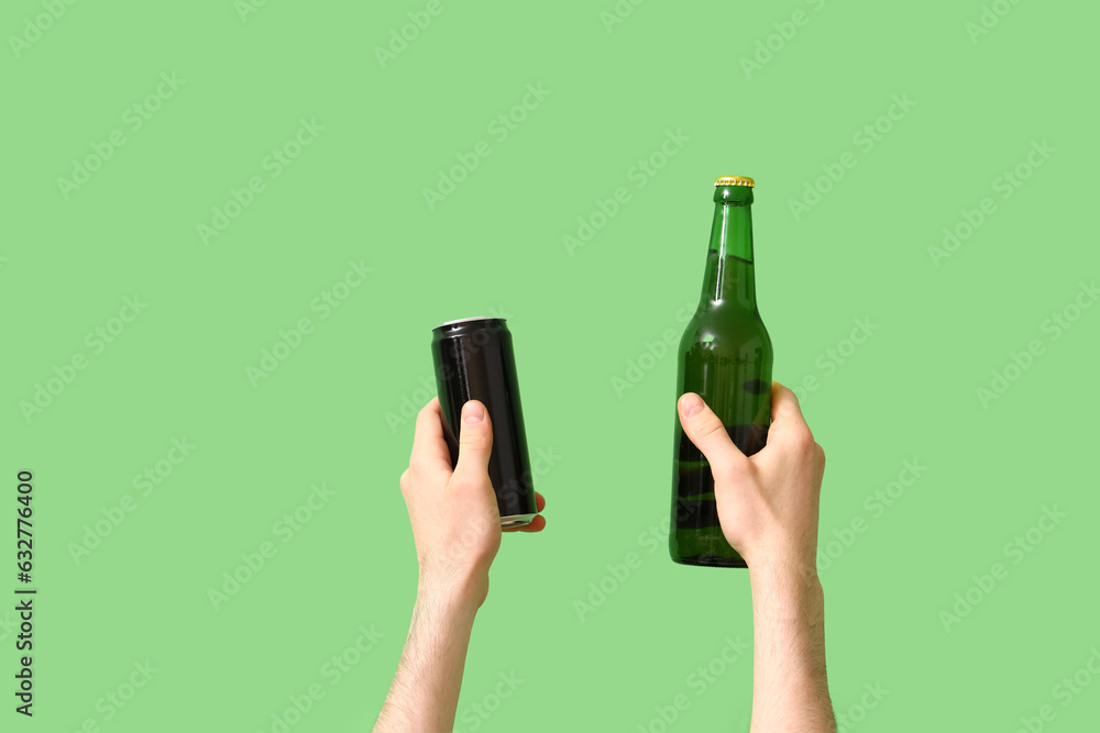 Man with bottle and can of beer on green background