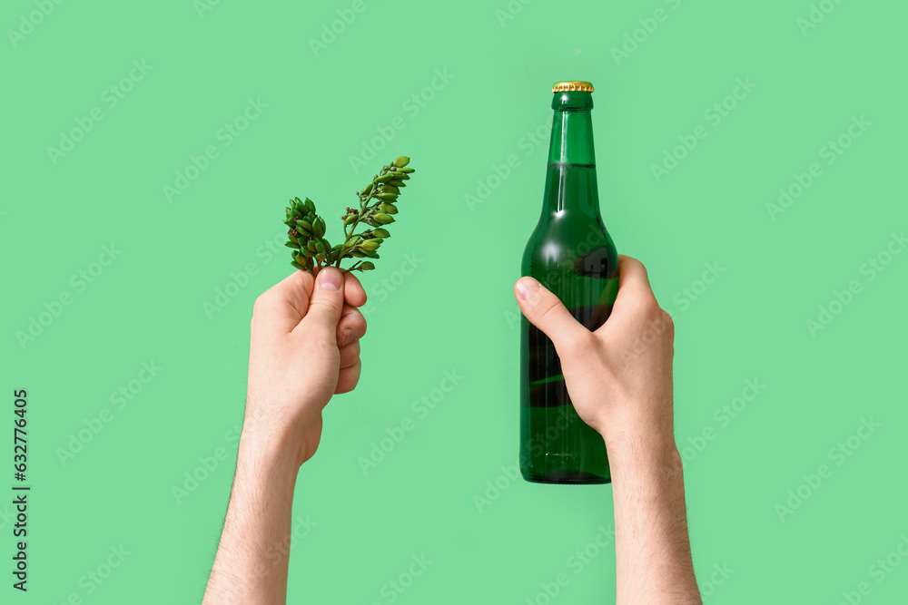 Man with bottle of beer and hop on green background