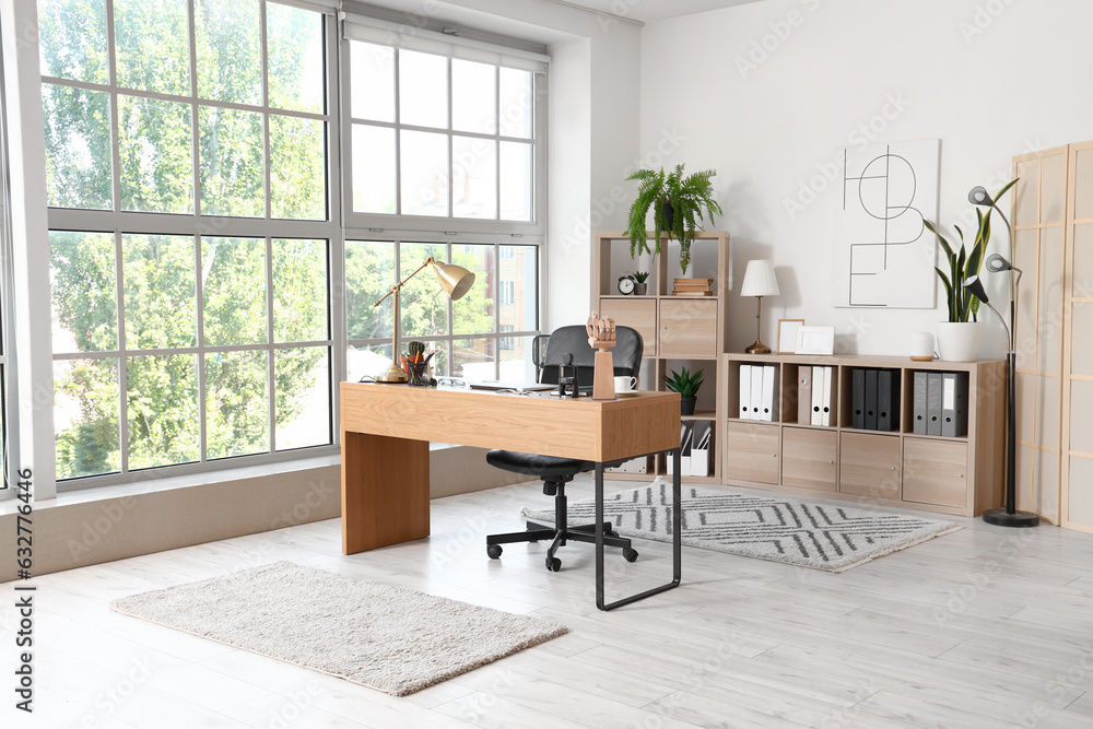 Interior of light office with modern workplace and shelving unit