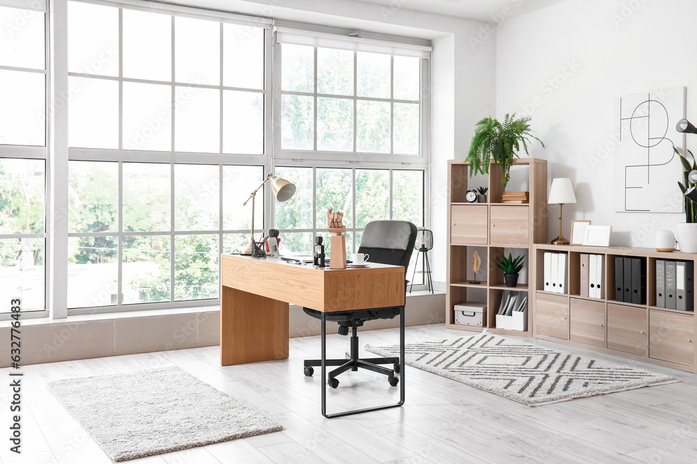 Interior of light office with modern workplace and shelving unit