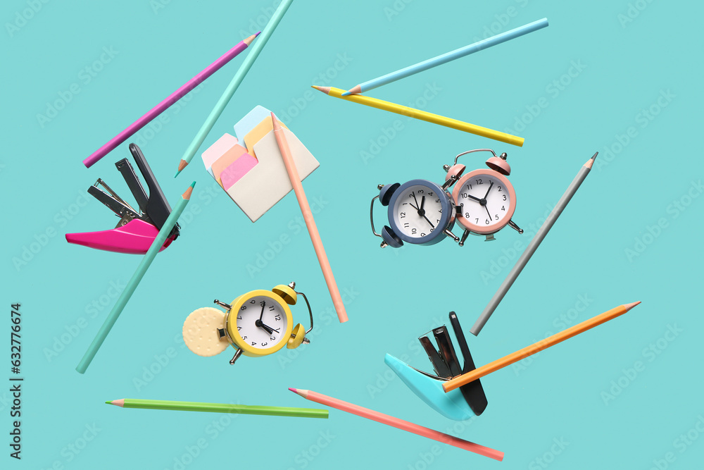 Different stationery and alarm clocks flying on color background