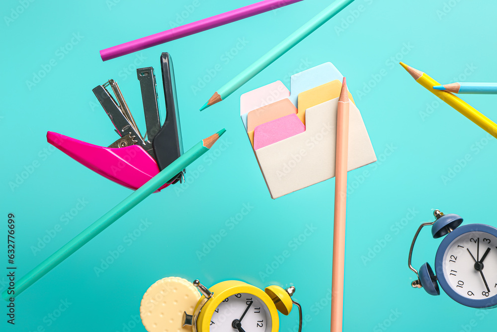 Different stationery and alarm clocks flying on color background