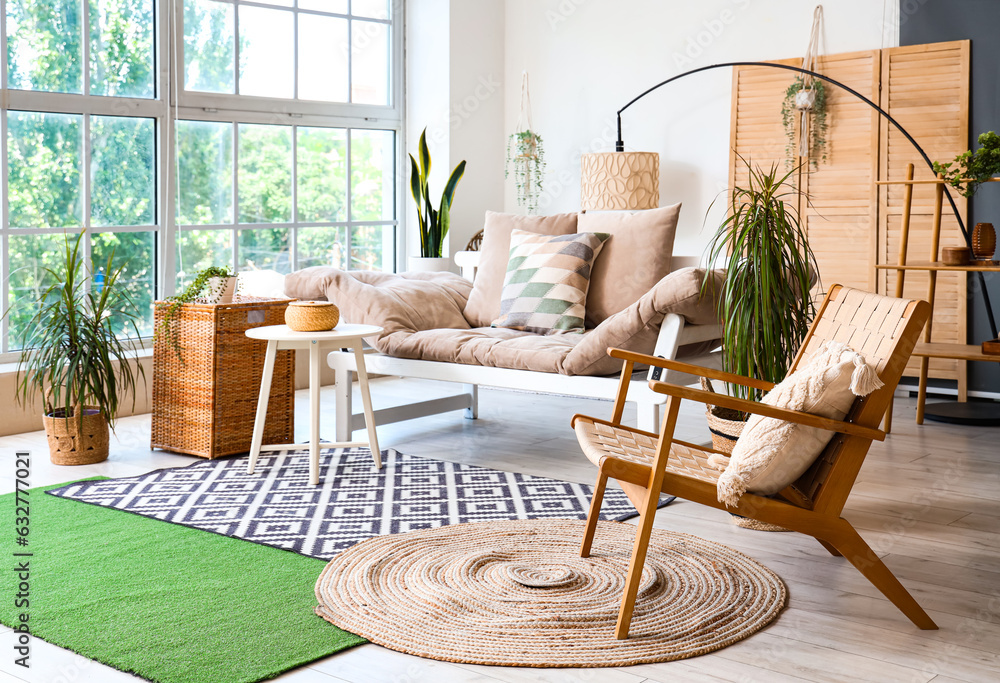 Interior of light living room with cozy sofa, armchair and houseplants