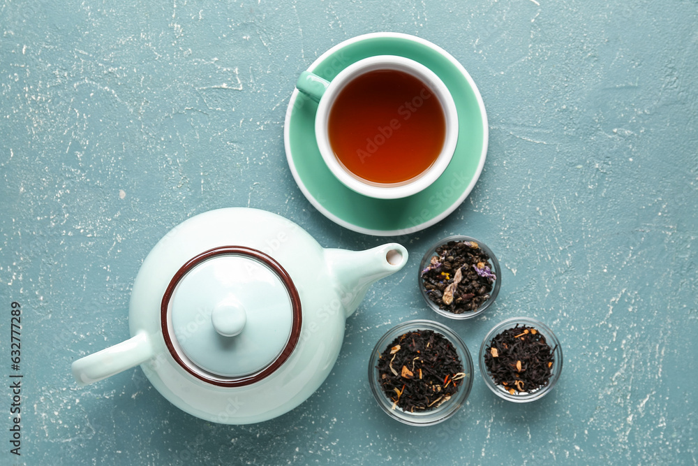 Teapot, different types of tea and cup of beverage on color background