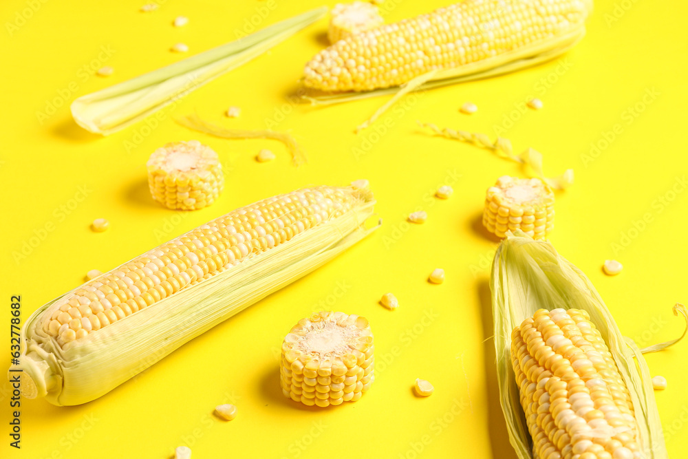 Fresh corn cobs and seeds on yellow background