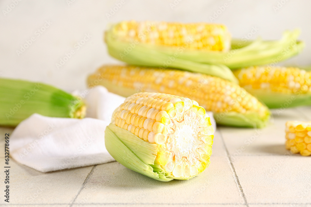 Fresh corn cobs on white tile table