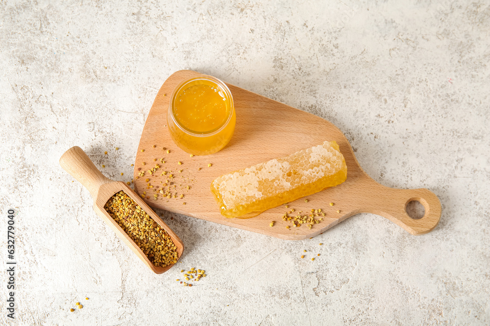 Wooden board with jar of honey, comb and bee pollen on light background