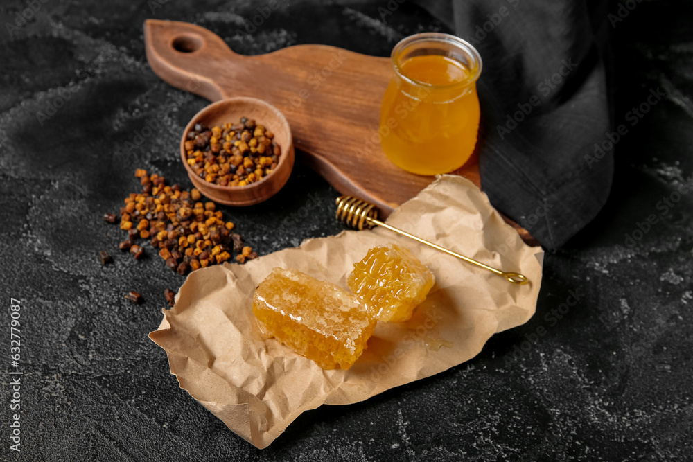 Paper sheet with fresh honeycombs and beebread on dark background