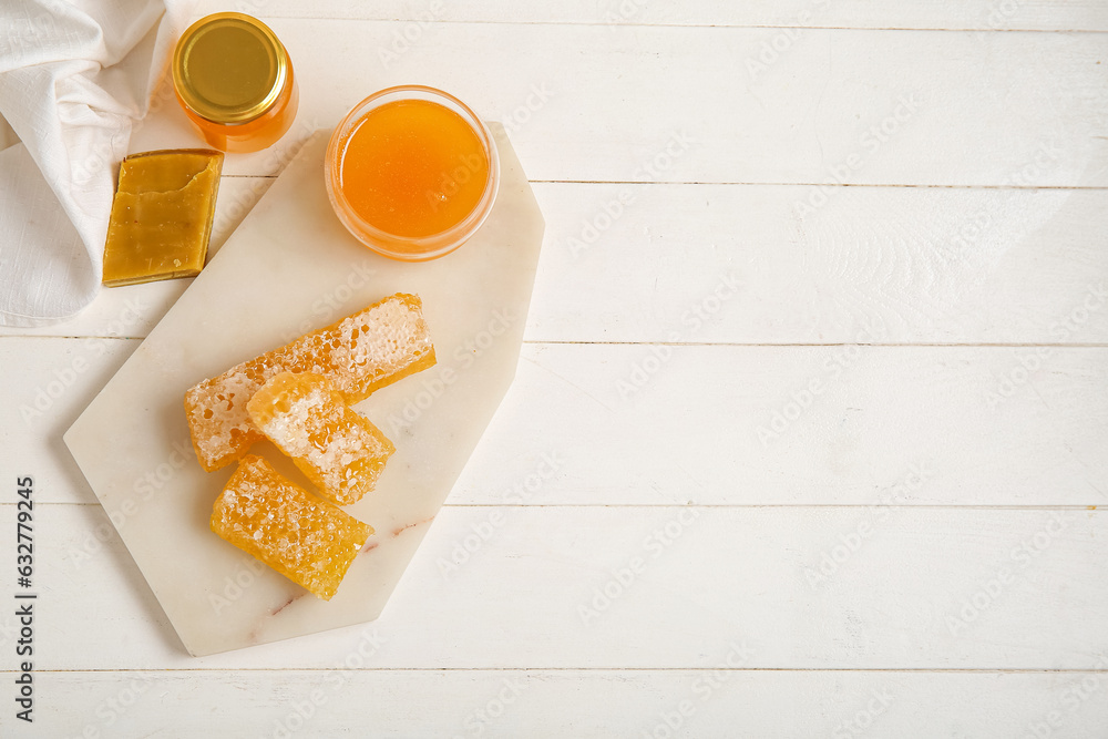 Board with honey, combs and bee wax on light wooden background