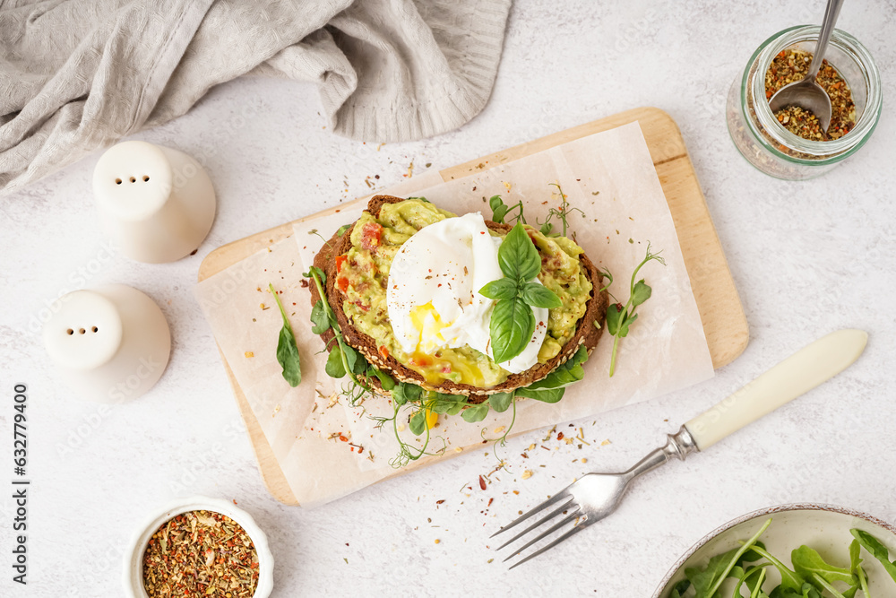 Wooden board of tasty sandwich with egg on light background