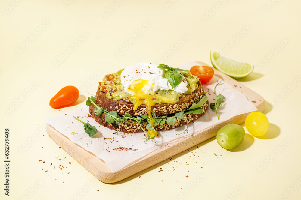 Wooden board of tasty sandwich with egg on yellow background