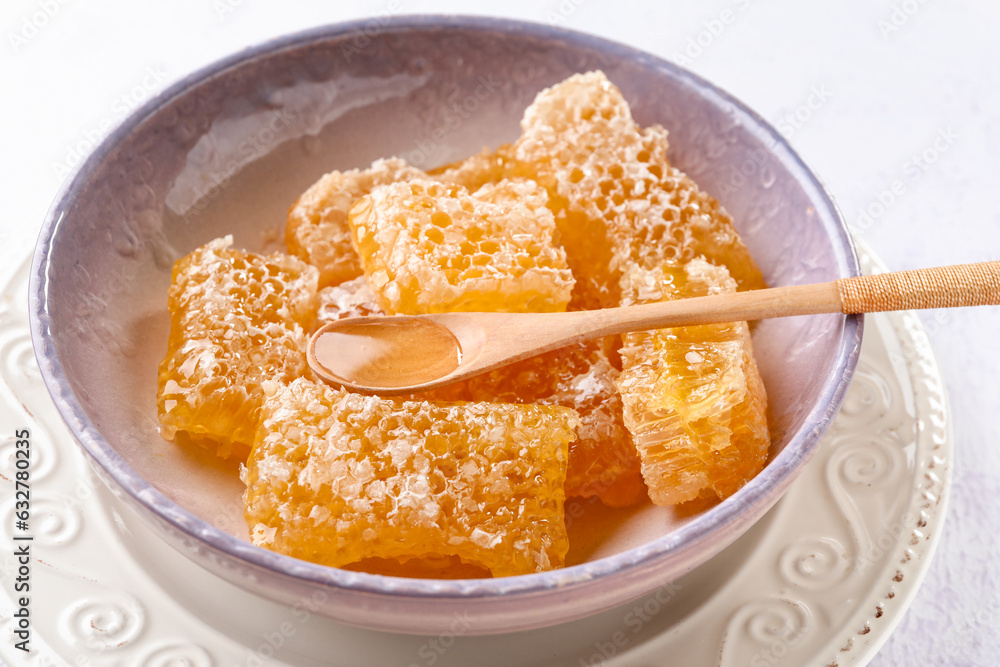 Bowl with sweet honeycombs on white background