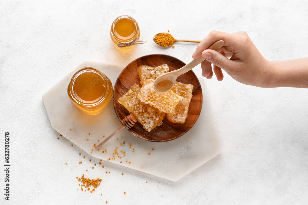 Woman pouring sweet honey onto combs on white background