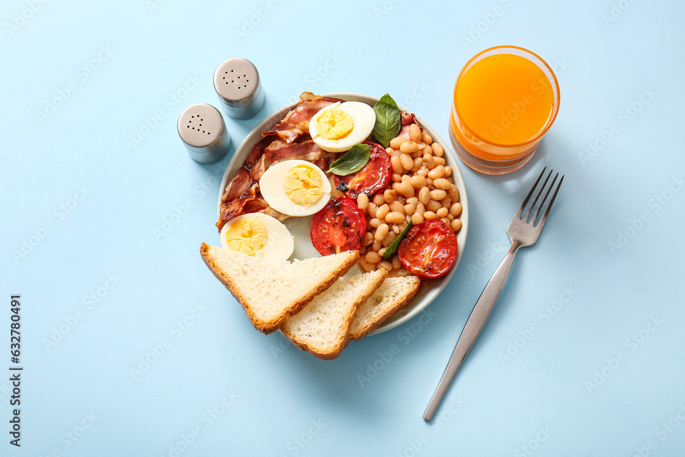 Plate with tasty English breakfast and glass of juice on blue background