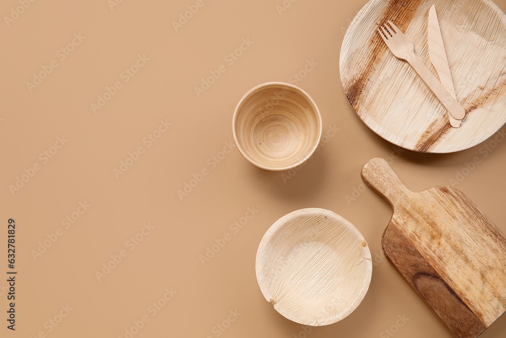 Different wooden tableware on beige background