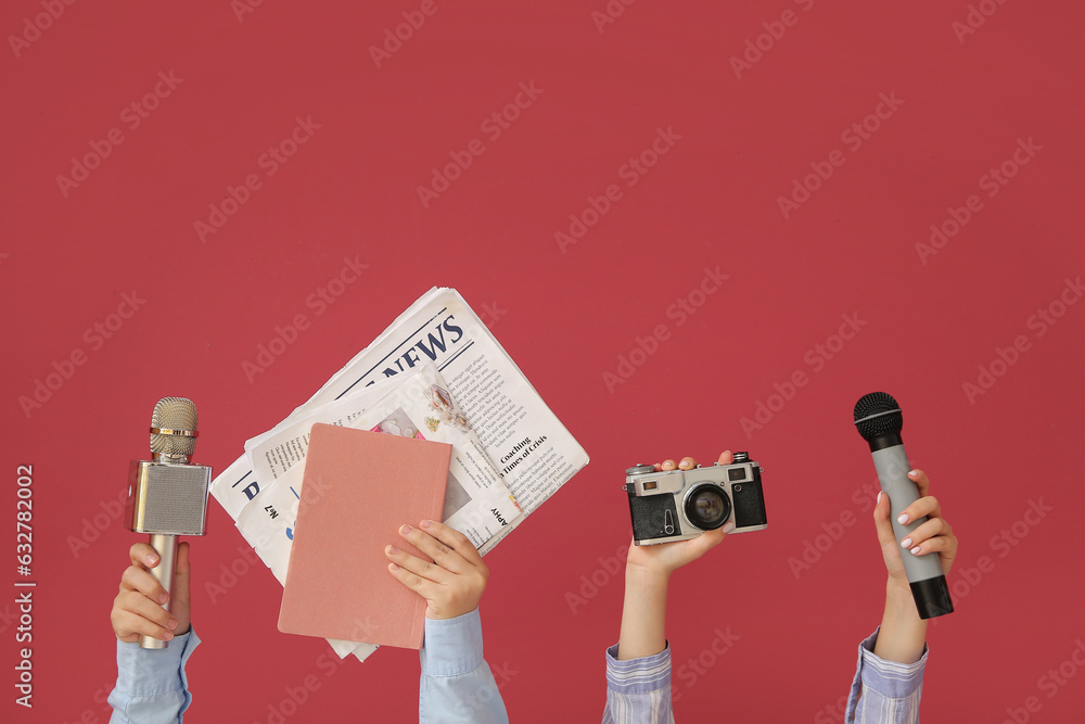 Female hands with newspapers, microphones and photo camera on color background