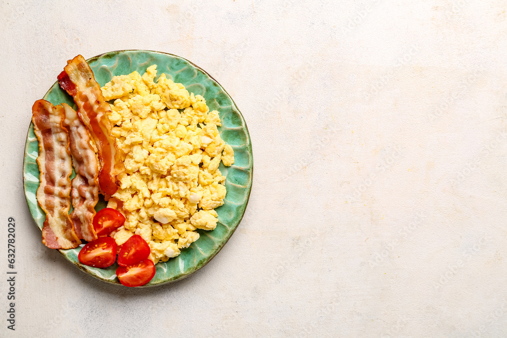 Plate of tasty scrambled eggs with bacon on light background