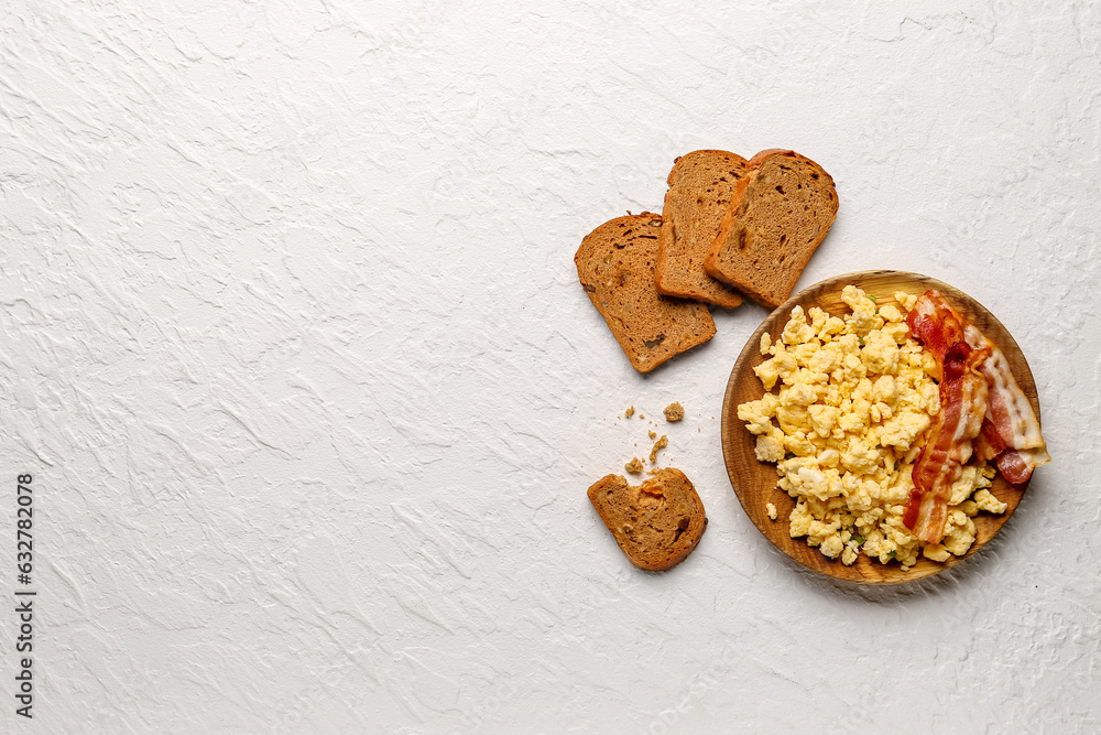 Plate of tasty scrambled eggs with bacon on white background