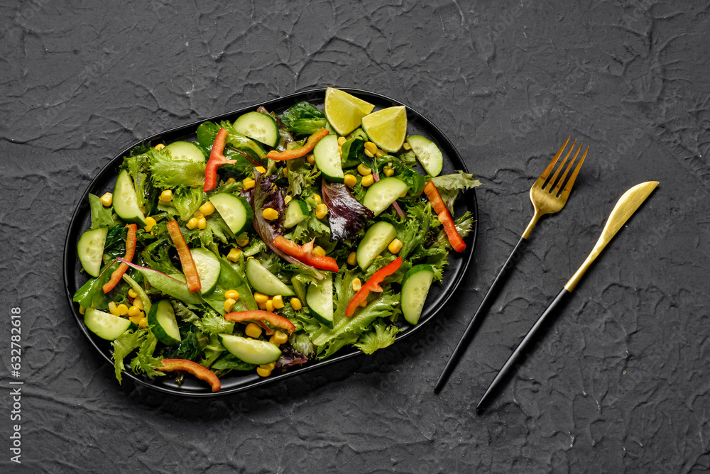 Plate with fresh vegetable salad on black background